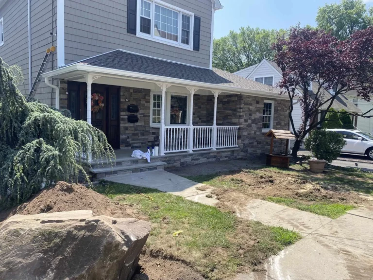 Renovated residential home with stone siding, new porch, and landscaping work in progress on the front yard.